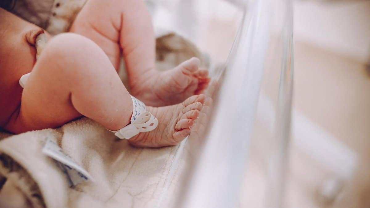Close-up of newborn baby feet with hospital ID bracelet, symbolizing new beginnings.