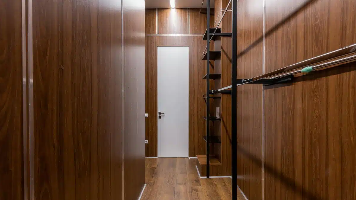 Empty black shelves and racks placed near brown walls in corridor with minimalist style with white door and glowing illumination