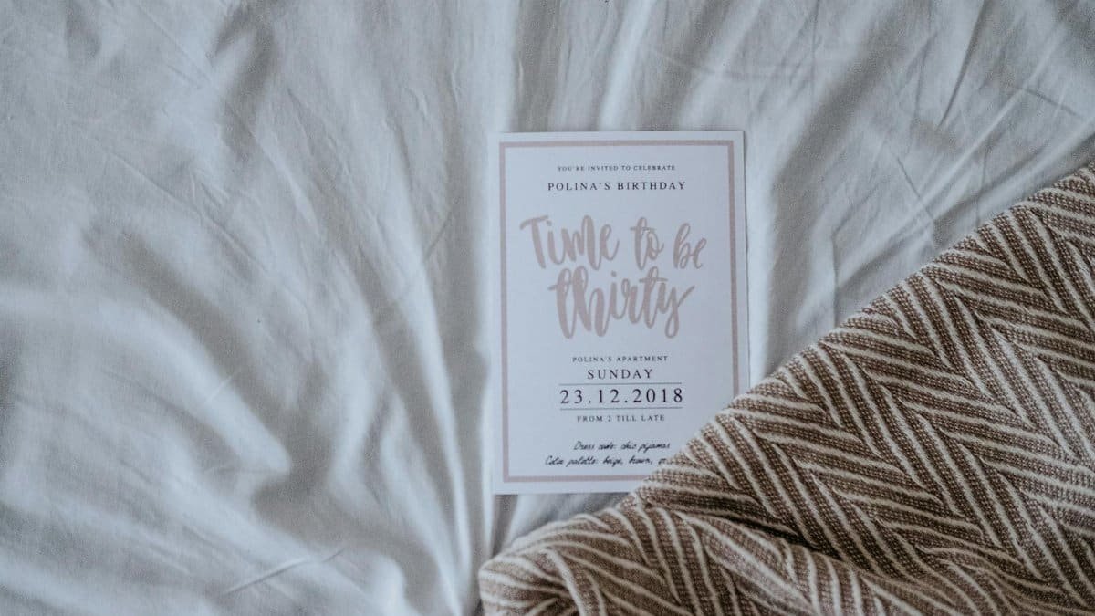 A chic invitation card for a 30th birthday celebration resting on a soft fabric background.