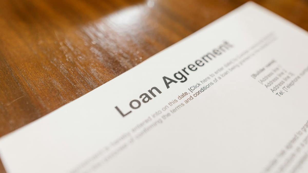 Detailed loan agreement document close-up on a wooden table representing legal and financial concepts.