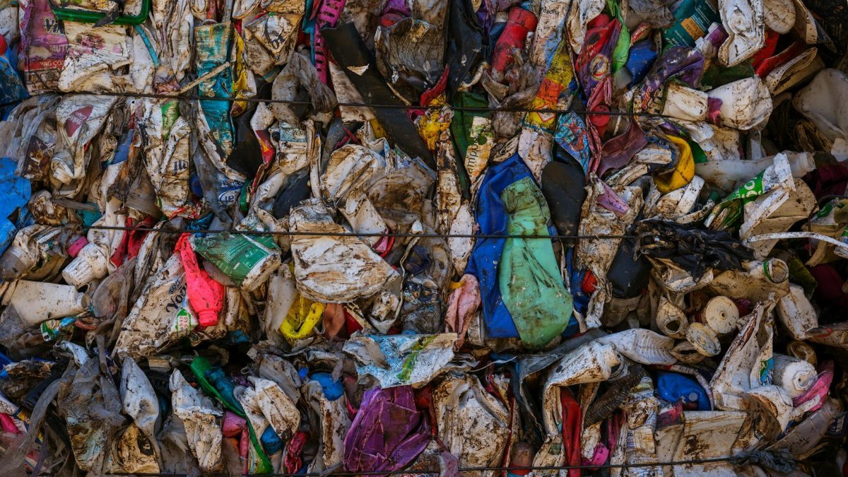 A visually striking wall of compressed, multicolored plastic waste highlighting recycling and consumerism concerns.