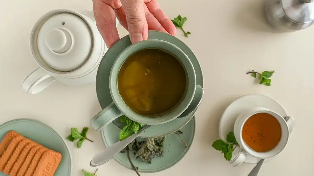 Elegant flat lay of a tea setting with biscuits and teapots on a white surface.