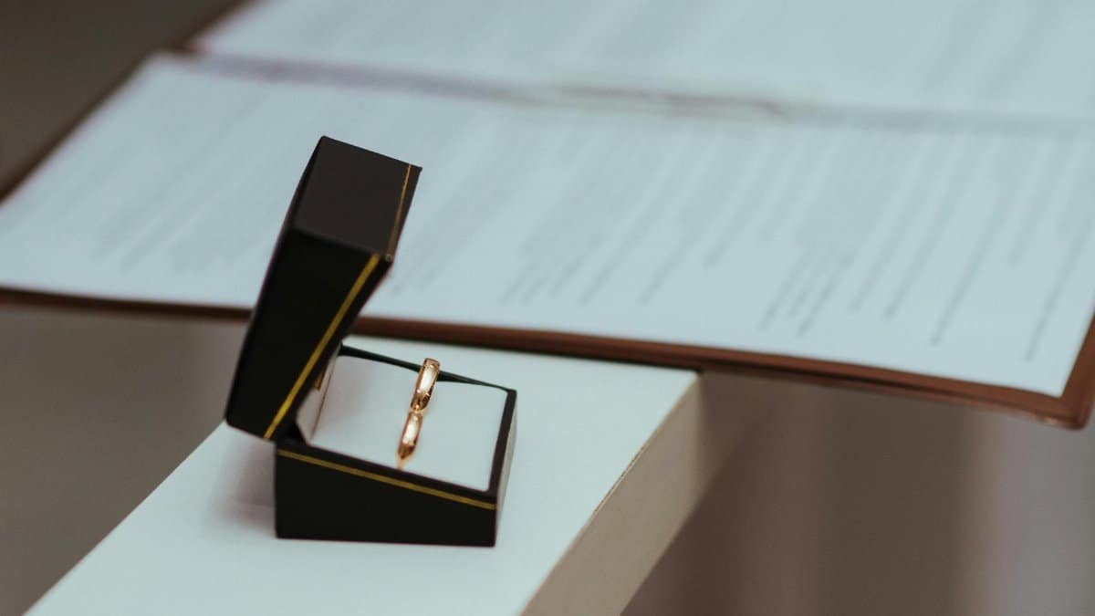 A pair of wedding rings in a black box next to important documents, symbolizing commitment.