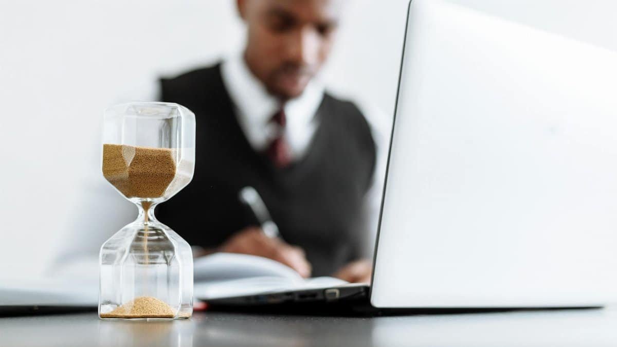 Businessman at desk with hourglass indicating time management and daily work routine.