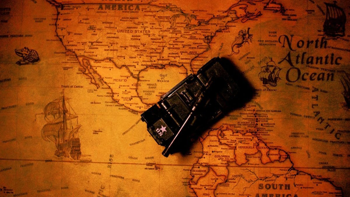 Artistic image of a vintage map showing North America with a toy tank on it. Rich tones and historical elements.