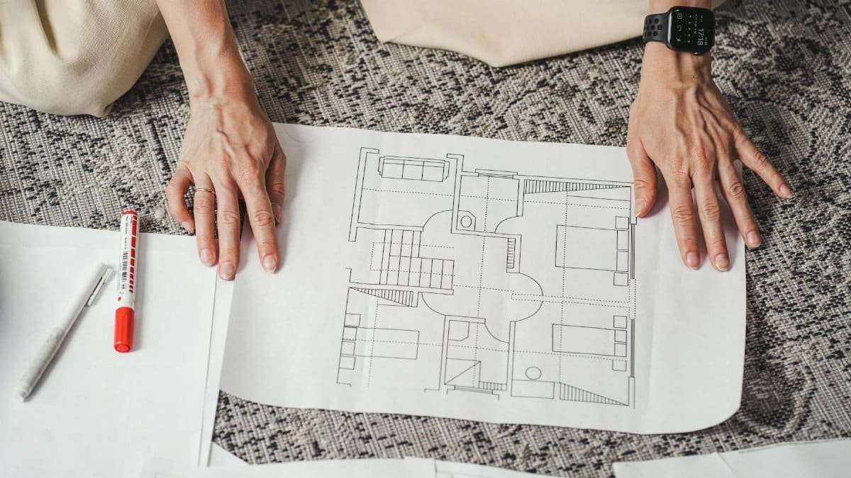 Hands on a detailed architectural floor plan paper, showcasing home design layout.