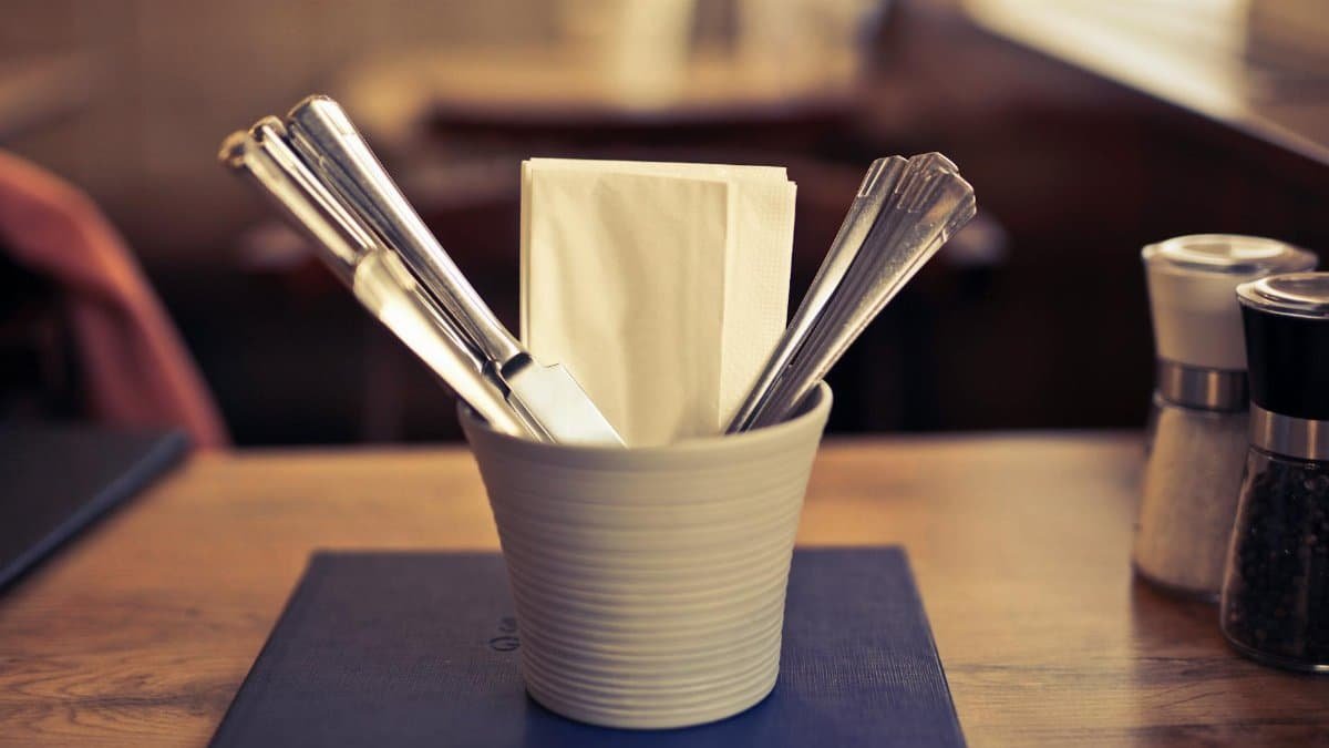 Close-up of elegant table with silverware and napkin in focus. Ideal for dining themes.