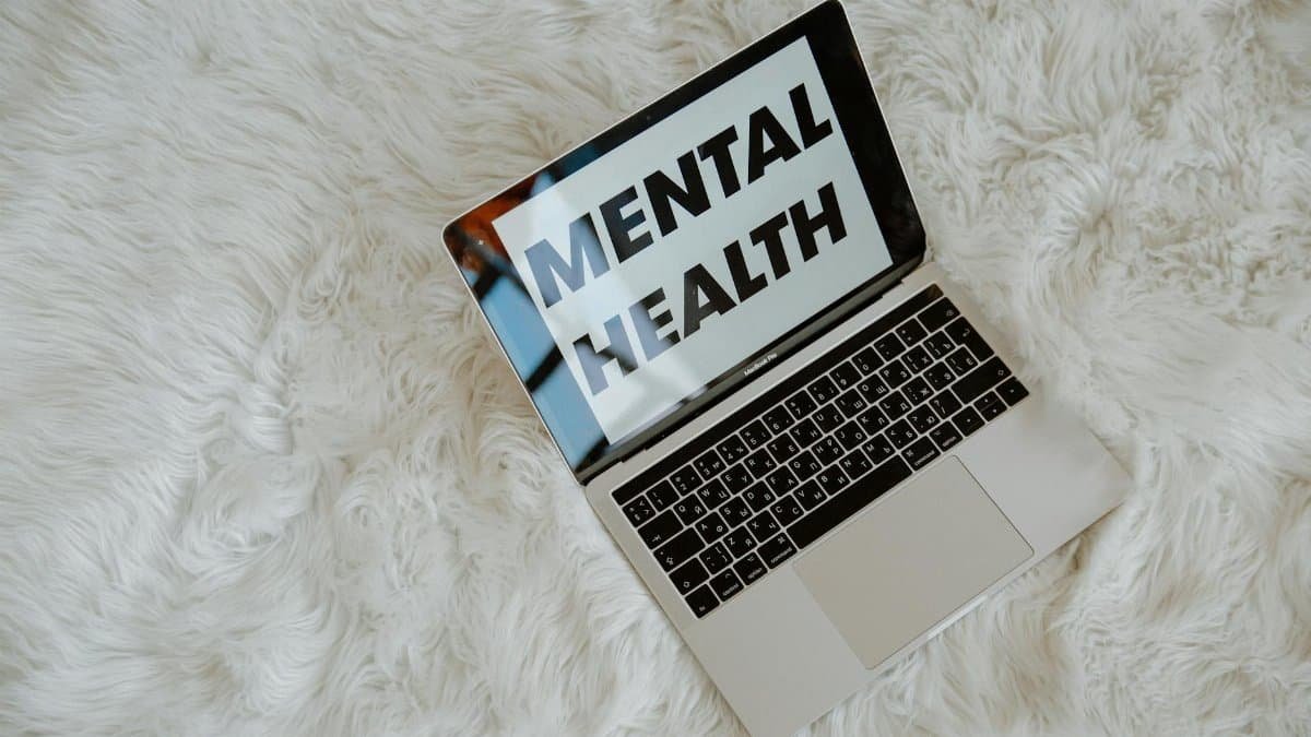 A laptop on a fluffy surface highlights the phrase 'Mental Health', emphasizing awareness.