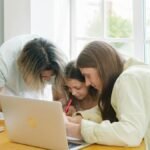 Parents helping their child with homework while sitting together at a table.