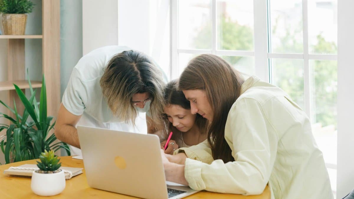 Parents helping their child with homework while sitting together at a table.
