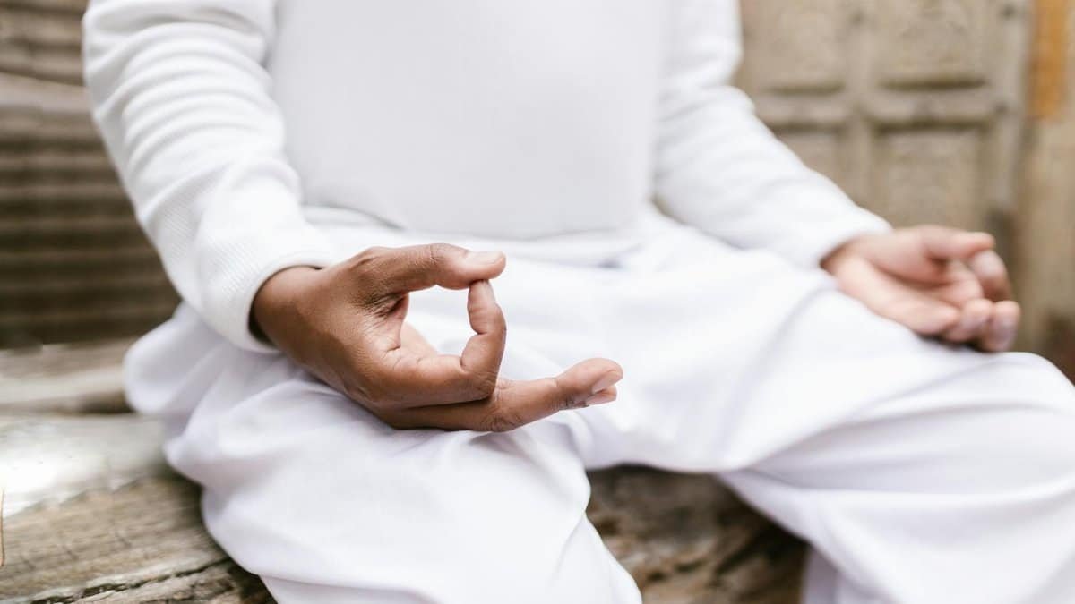 A serene person meditating outdoors in white clothing, focusing on mindfulness and spiritual balance.
