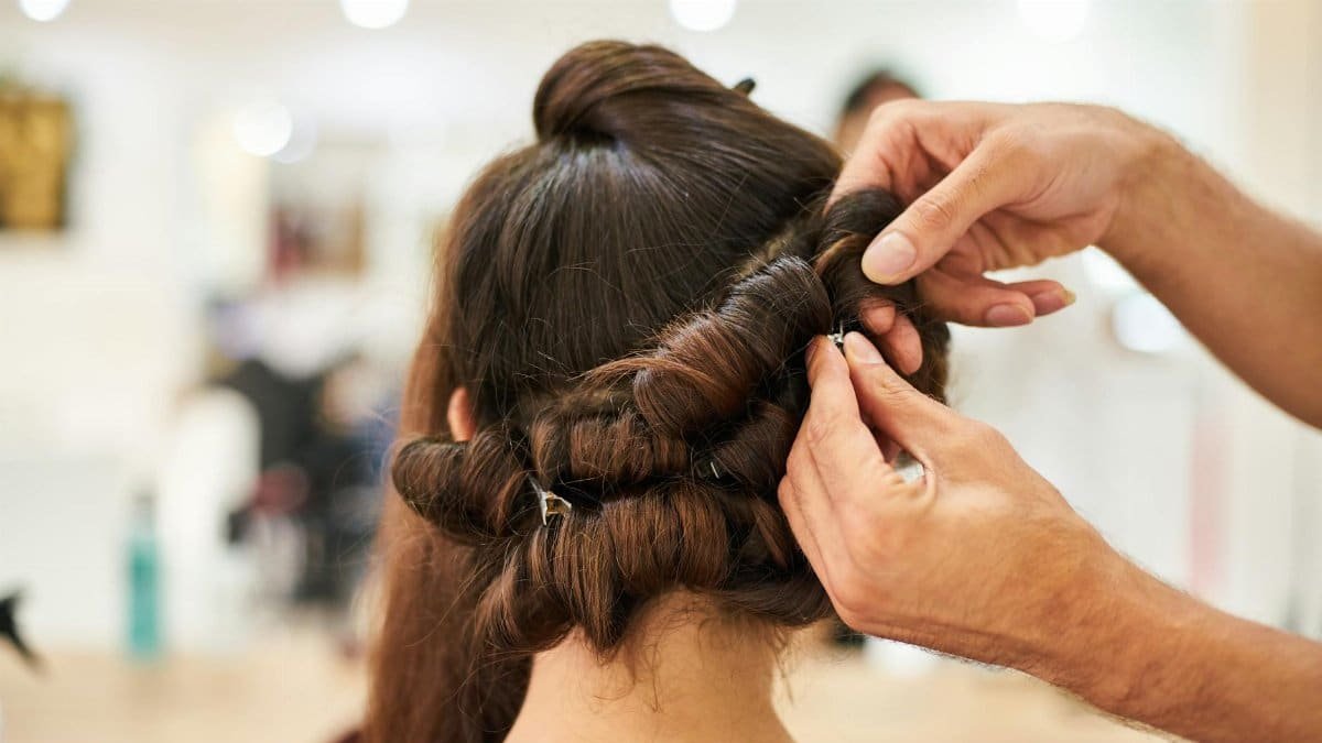 Close-up of a stylist crafting an intricate updo hairstyle in a modern salon.
