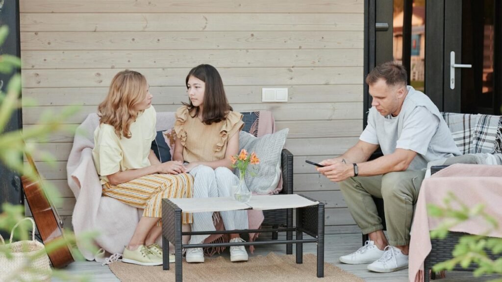 A family enjoying a relaxing day on their patio, engaging with digital devices.