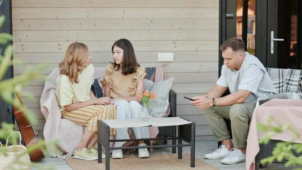 A family enjoying a relaxing day on their patio, engaging with digital devices.