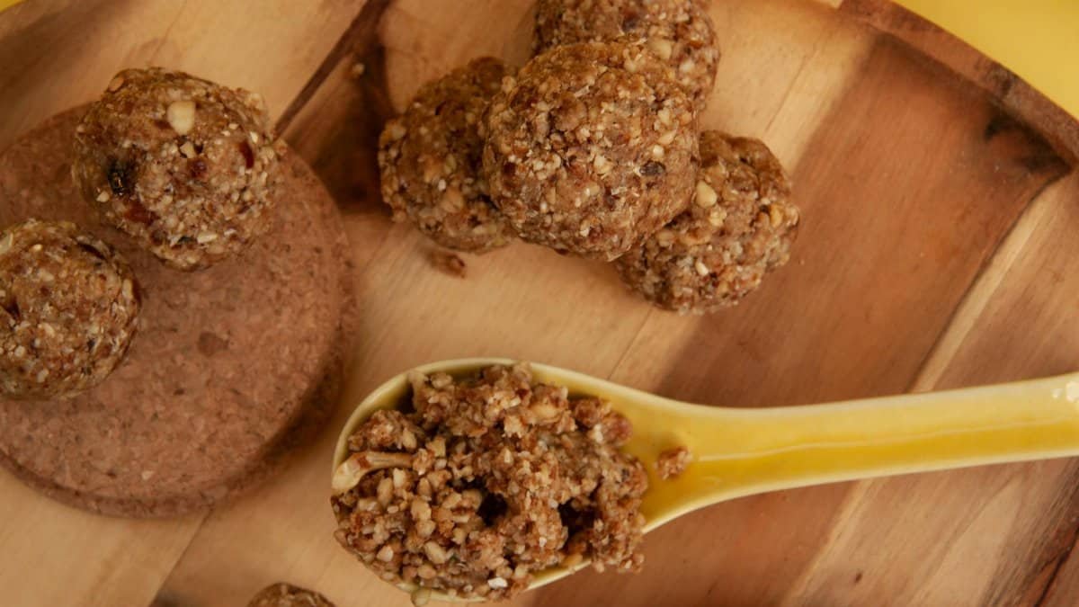Top view of homemade nut energy bites served on a wooden tray with a yellow spoon for healthy snack options.