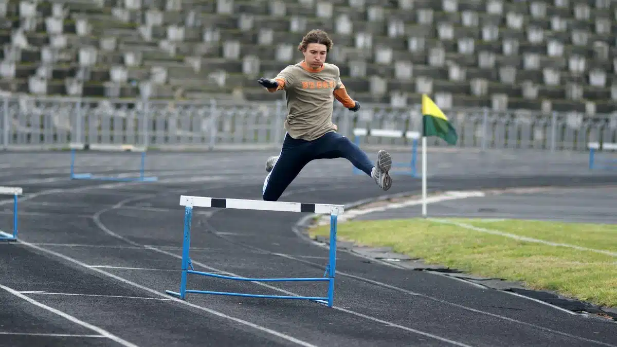Athlete demonstrating speed and agility while jumping hurdles during track event.