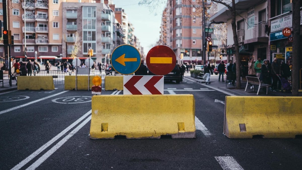City intersection in Barcelona with roadblocks and traffic signs during daylight hours.