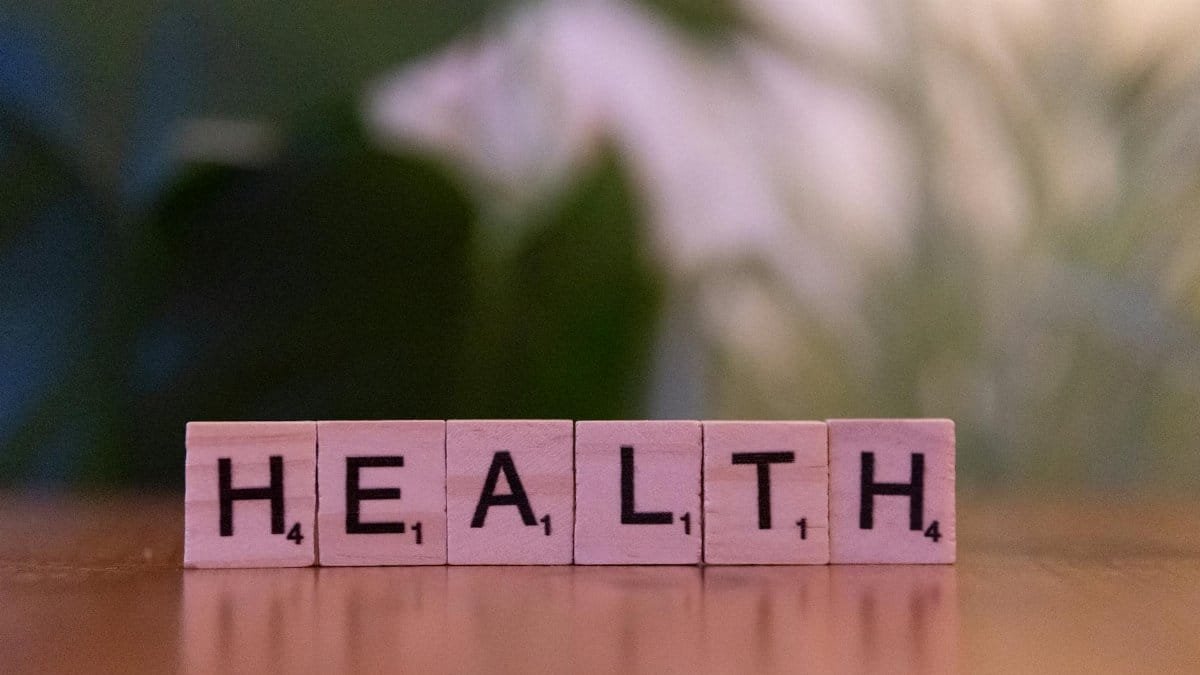 Close-up of Scrabble tiles spelling 'Health' on a wooden table with a blurred background.