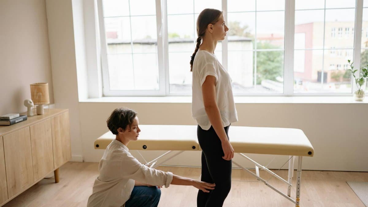 A physiotherapist assessing a client's posture in a bright, modern clinic.