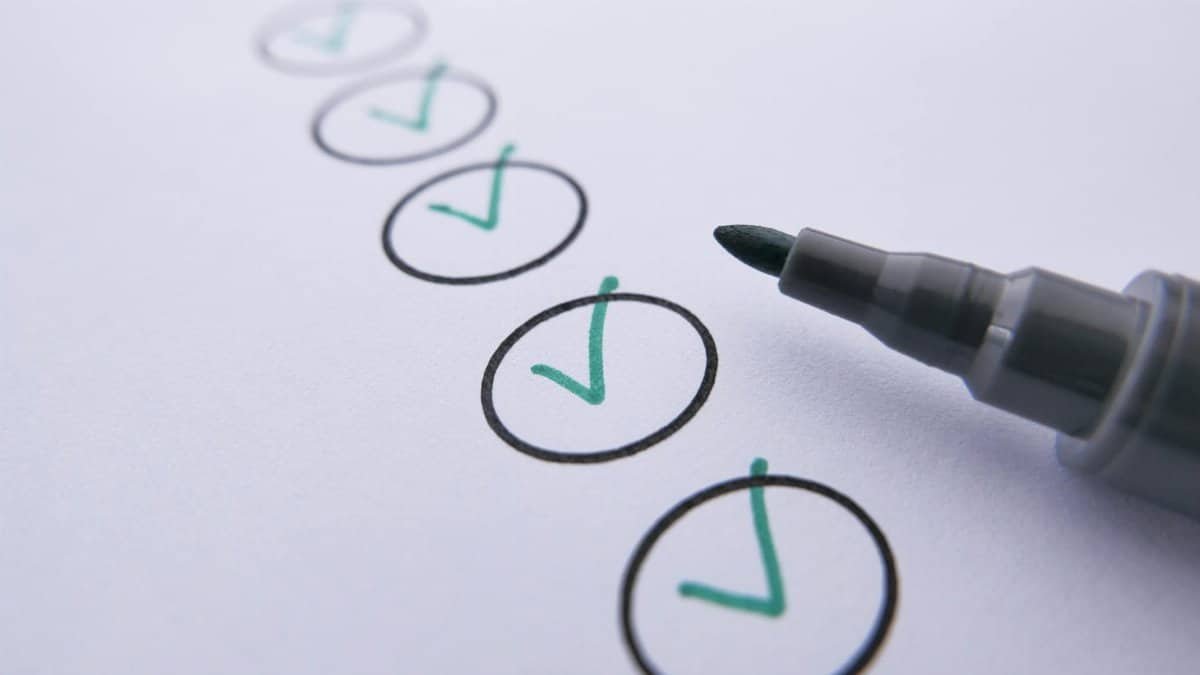 Close-up of a checklist with green checkmarks on white paper using a marker.