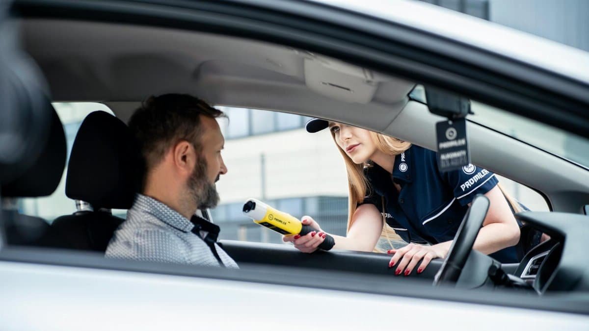 A police officer conducts a breathalyzer test on a male driver during a road safety check.