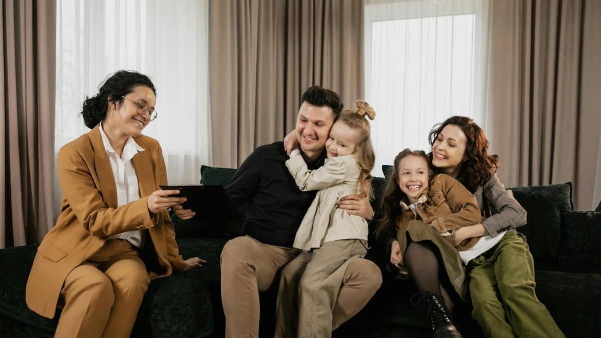 A cheerful family sitting in the living room with a real estate agent discussing a new home purchase.