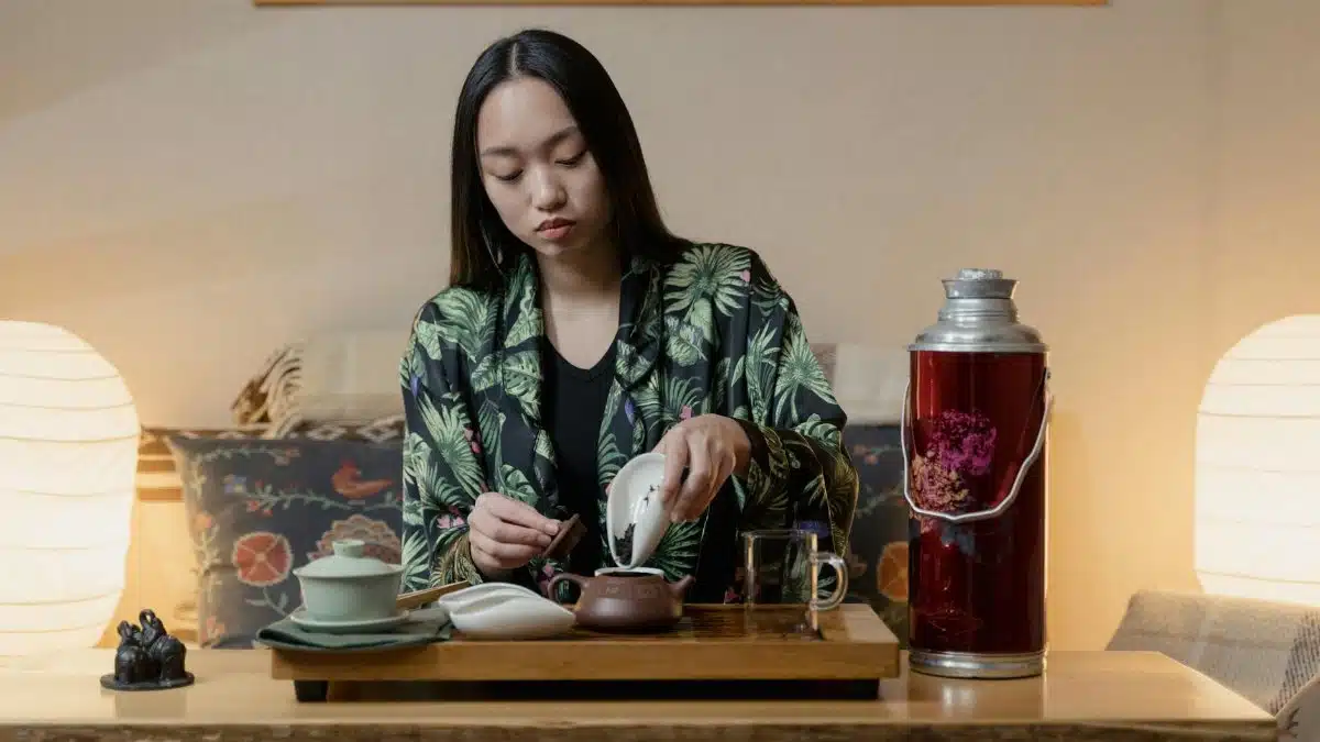 Woman performing a traditional tea ceremony indoors, creating a calm atmosphere.
