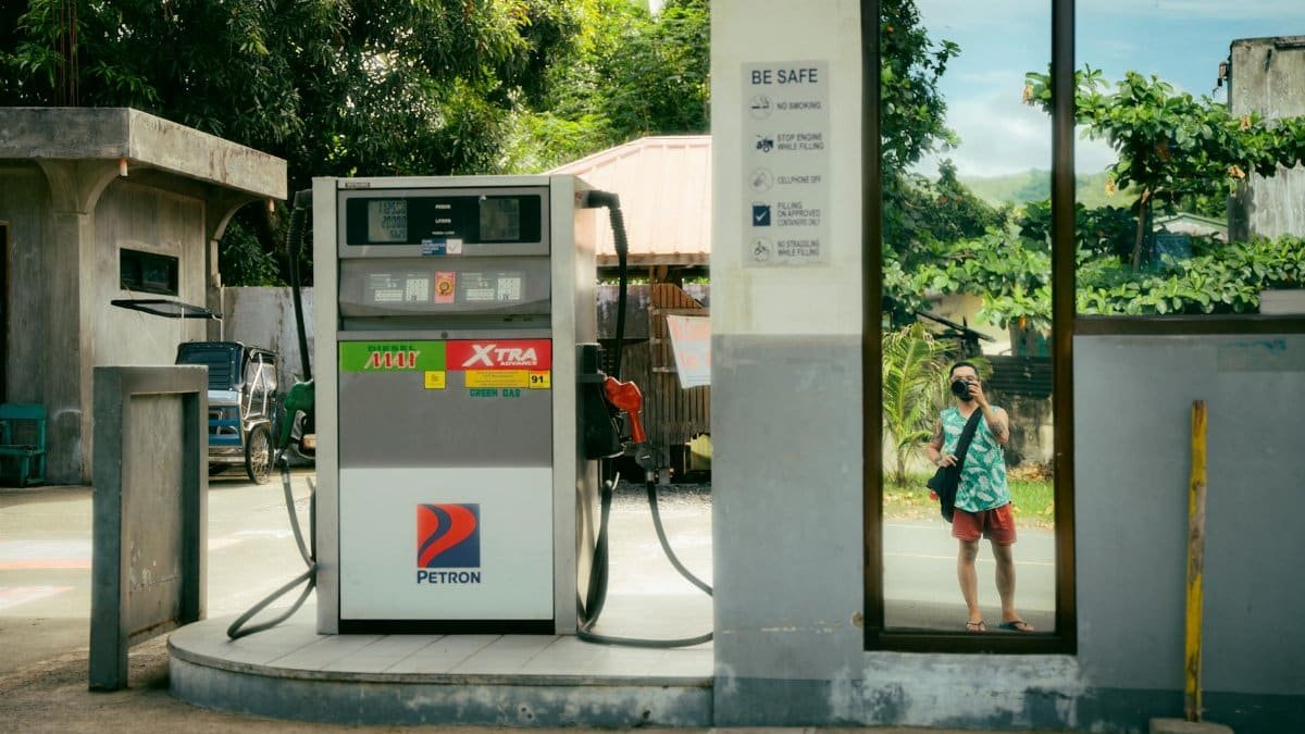 A gas station with a reflection of a person taking a selfie in a rural area.