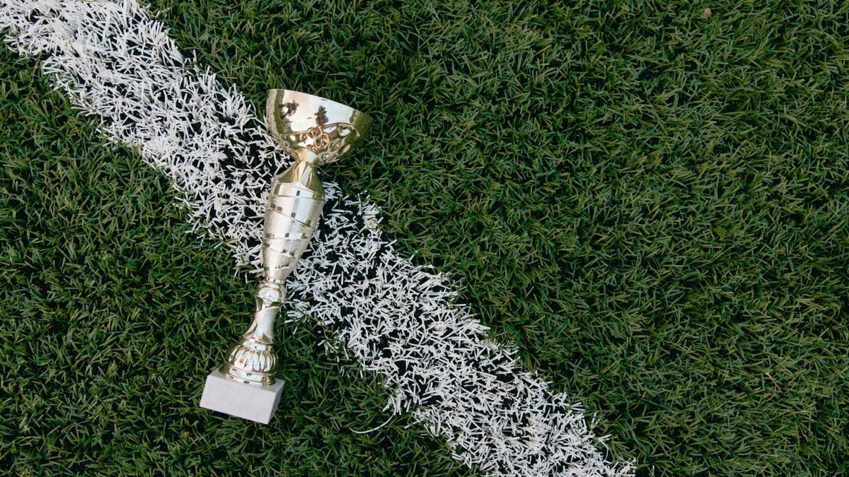 A gold trophy placed on green grass beside a white field line.