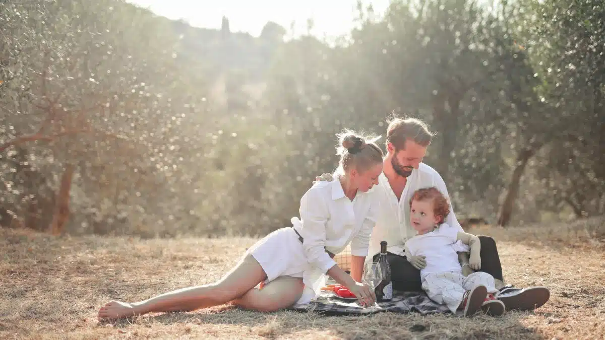 Happy family enjoying a picnic in an olive grove under the sun. Perfect for lifestyle and outdoor themes.