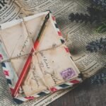 Old handwritten letters with vintage stamps and lavender on a newspaper background.