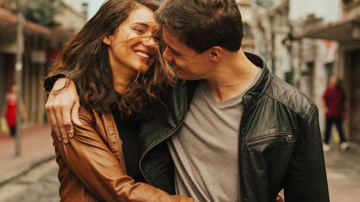 A joyful couple embracing and smiling on a city street, capturing love and happiness.