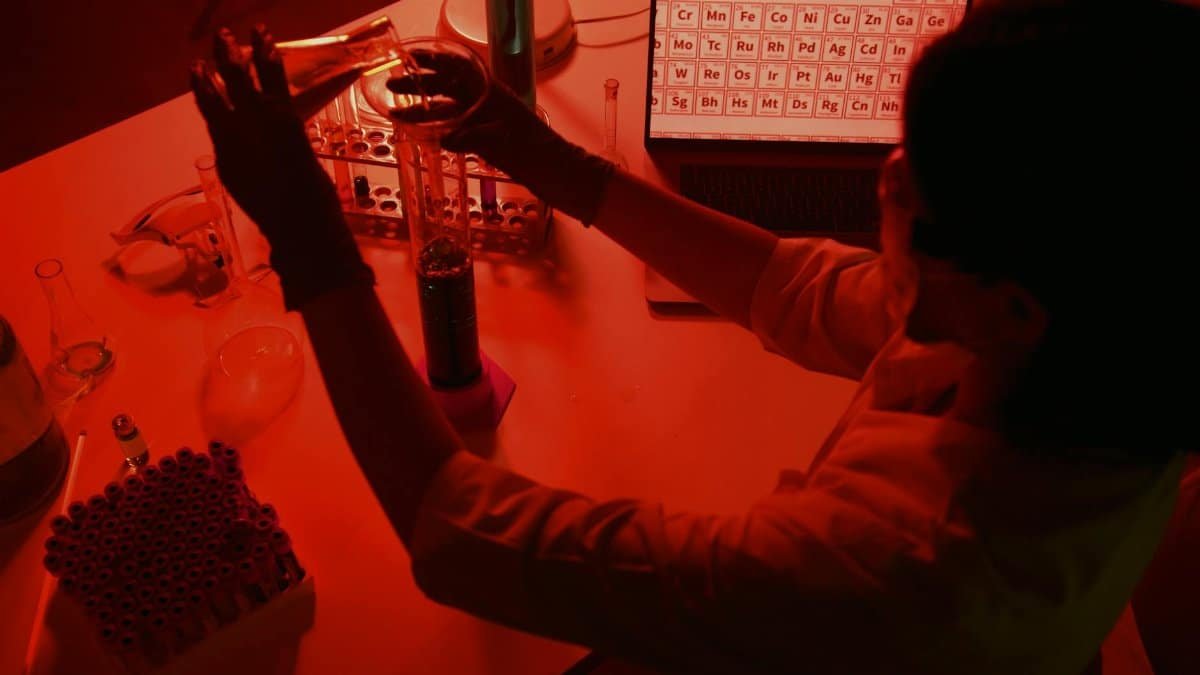 A scientist conducting experiments in a red-lit laboratory with various lab equipment.