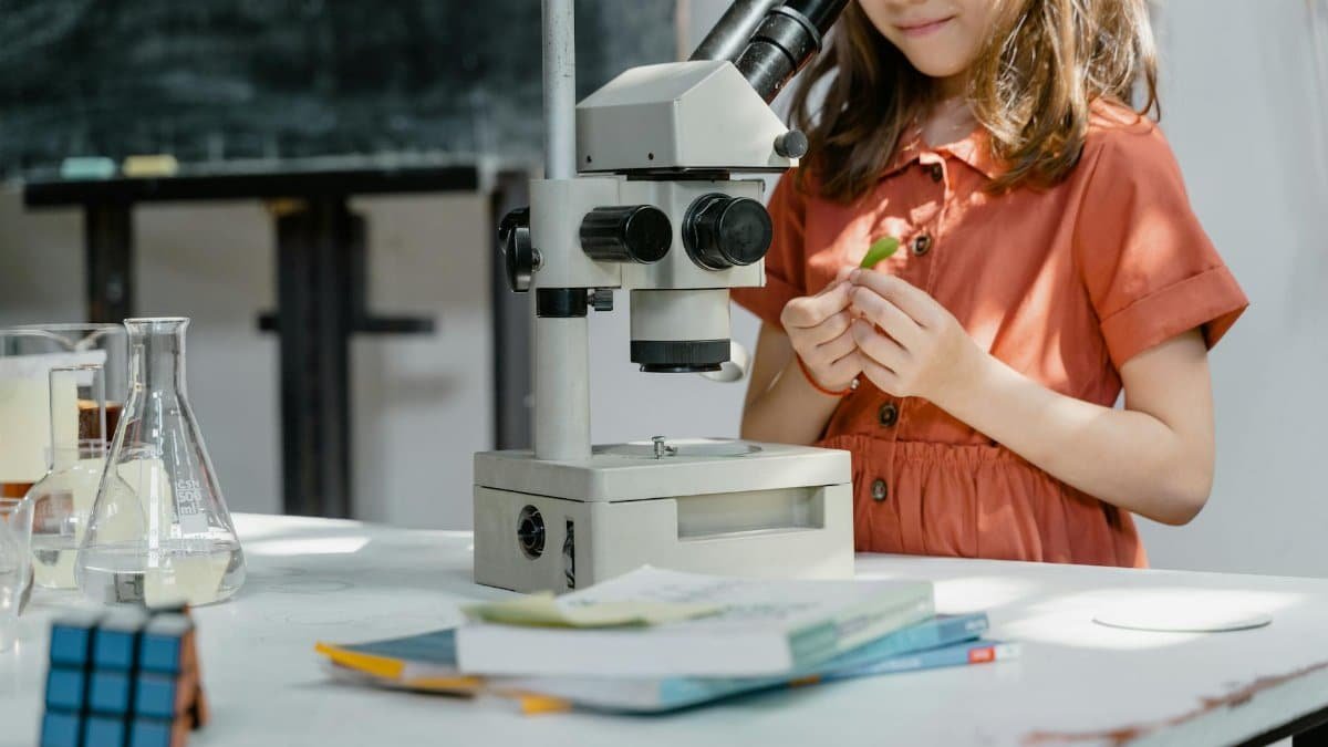 Young girl exploring science with a microscope and lab equipment indoors.