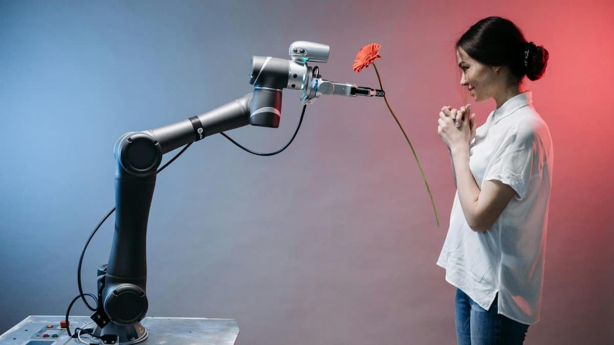 A robotic arm offers a flower to a woman in a display of technology and human connection.