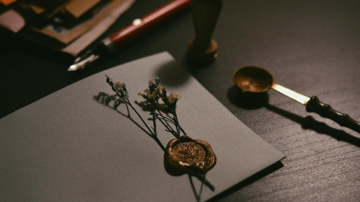 A vintage letter with wax seal and flowers on a desk, evoking nostalgia.