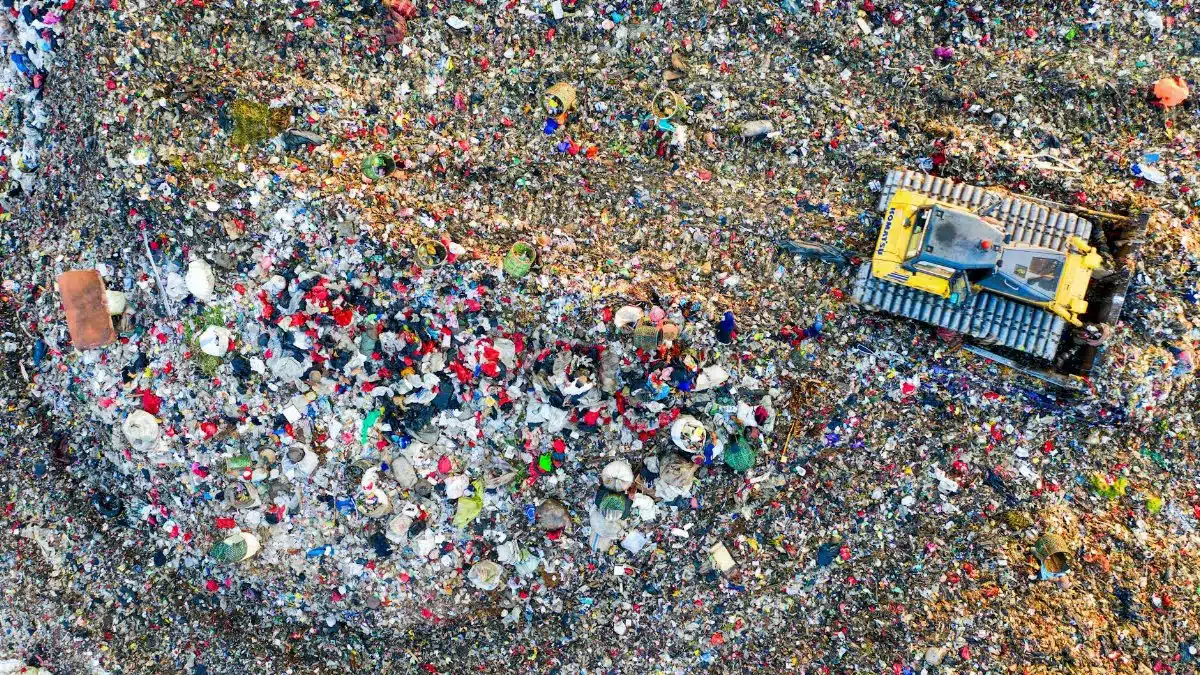 Aerial shot of a landfill site in West Java, Indonesia with visible waste management activity.