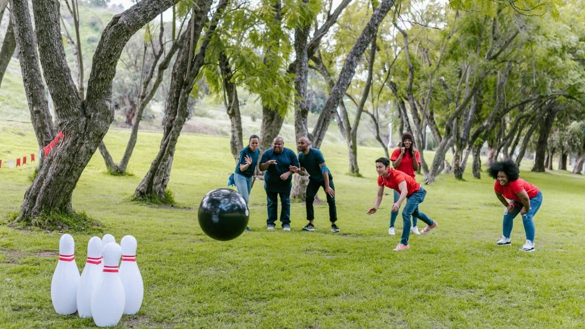 Group enjoying an outdoor team building event with bowling in a park setting.