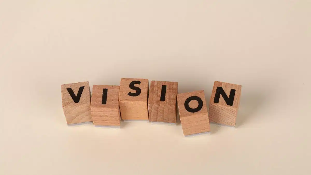 Wooden blocks with black letters spelling 'VISION' on a light beige background, symbolizing foresight and goals.