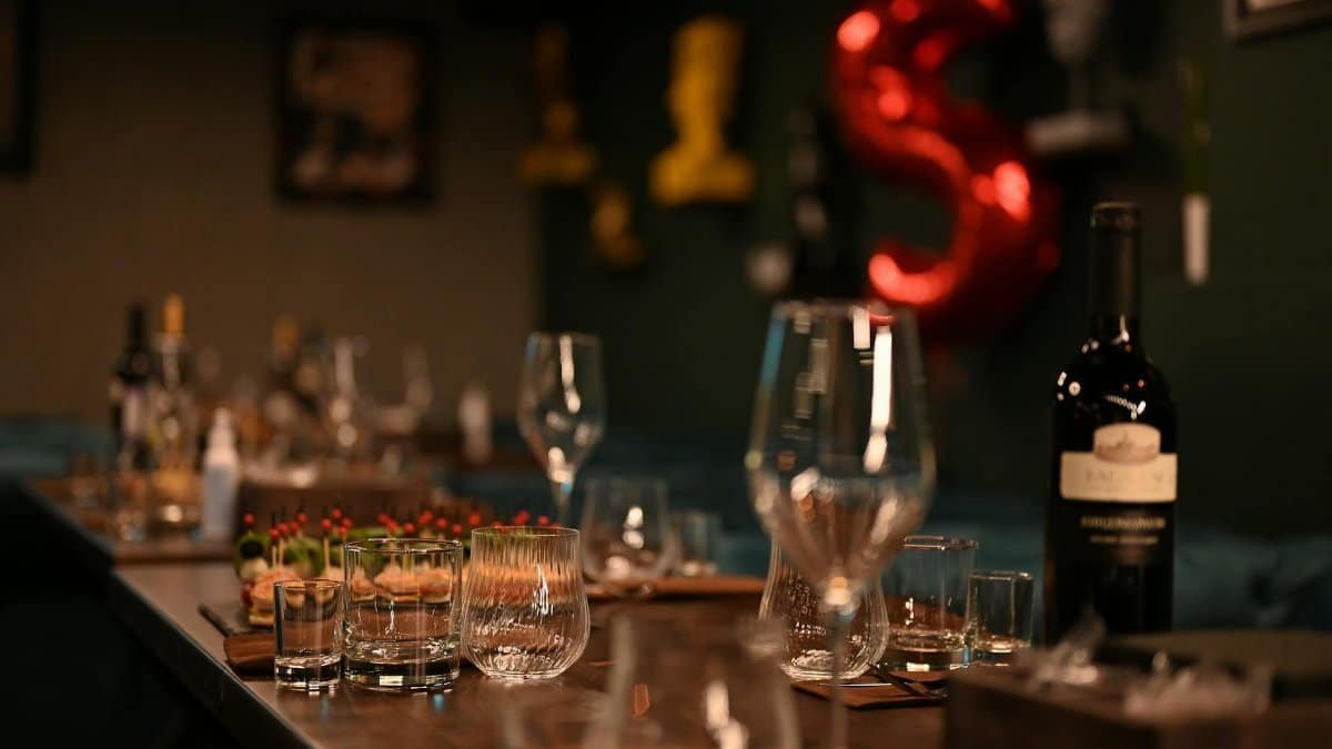 An indoor table setup featuring wine bottles and glassware, creating an elegant ambiance for a dinner event.