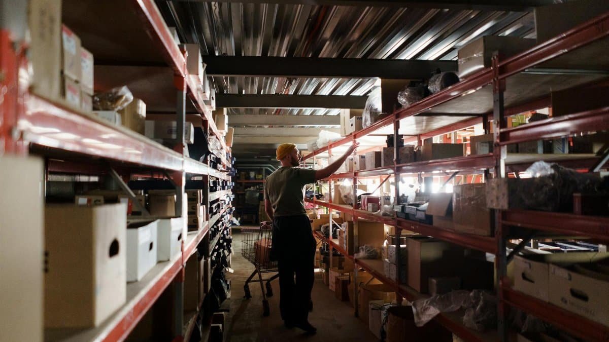 A warehouse worker arranging inventory on metal shelves in a storage facility