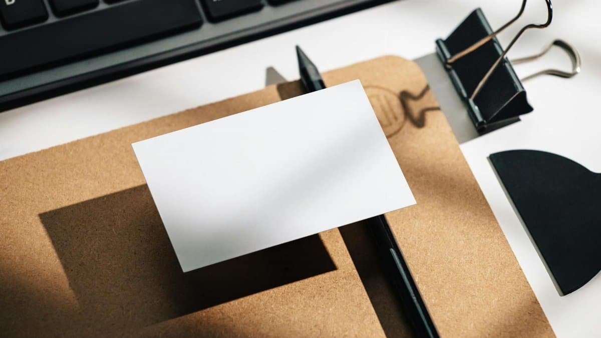 Flat lay of minimalist office supplies with a blank card, keyboard, and binder clip.