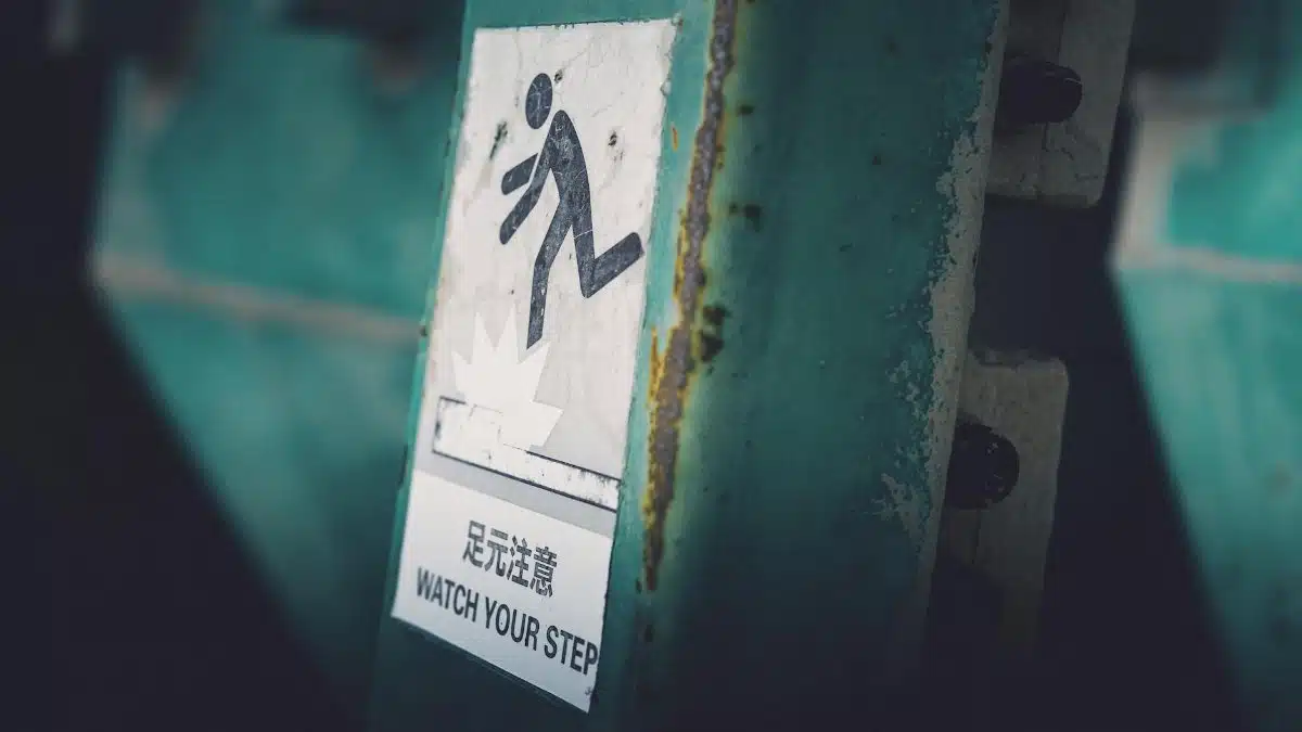 Dimly lit caution sign indicating 'Watch Your Step' in urban setting.