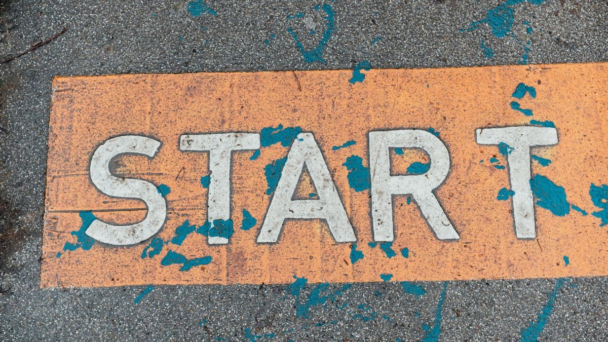 A worn orange start line painted on urban pavement with blue splatters.