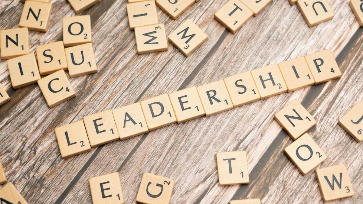 Wooden letter tiles spelling 'LEADERSHIP' on a wooden surface, symbolizing leadership qualities and skills.