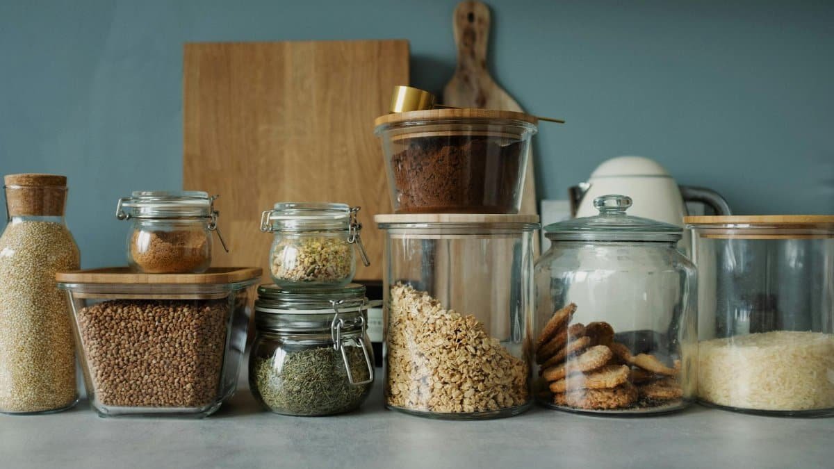 Neatly arranged glass jars with cookies, oats, spices, and ingredients on a kitchen counter.