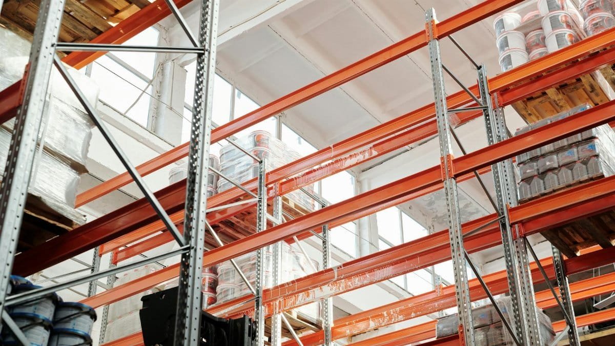Bright warehouse interior with orange metal shelving units and stored goods.