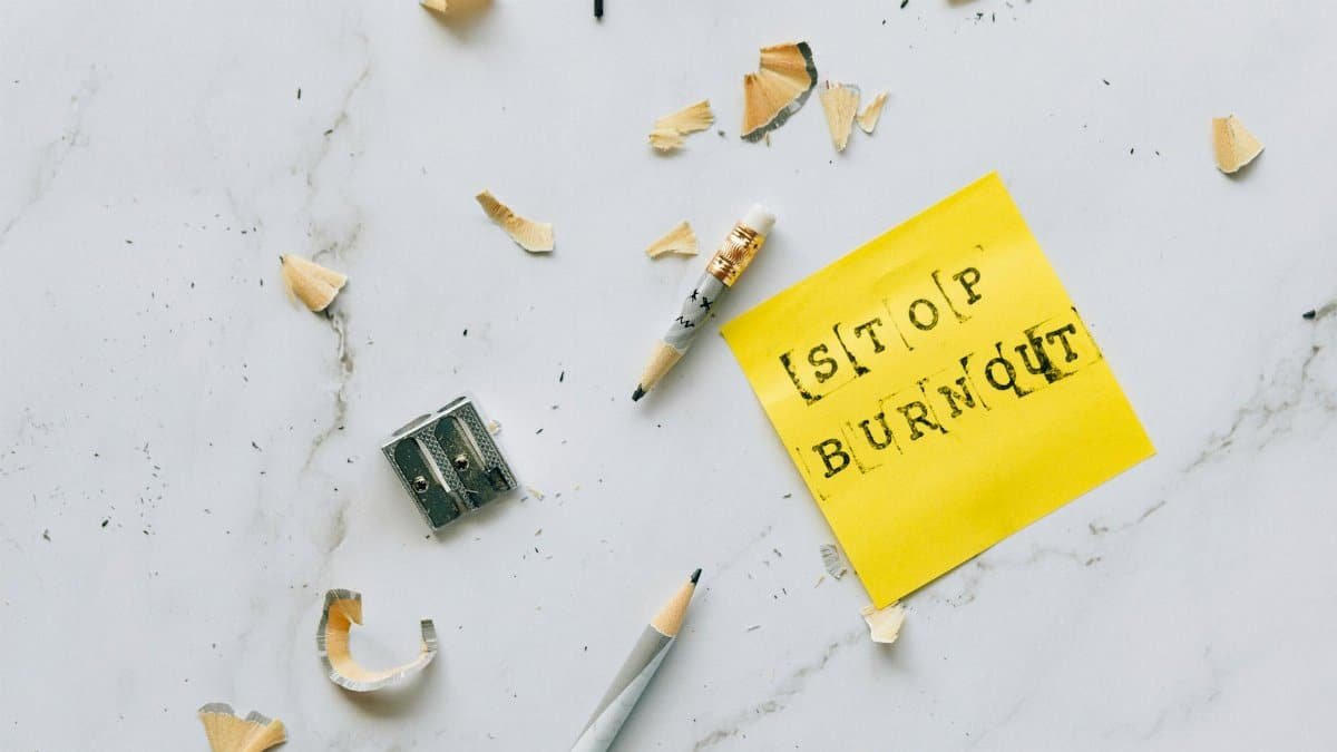 Pencil and shavings with 'Stop Burnout' note on marble surface convey stress relief concept.