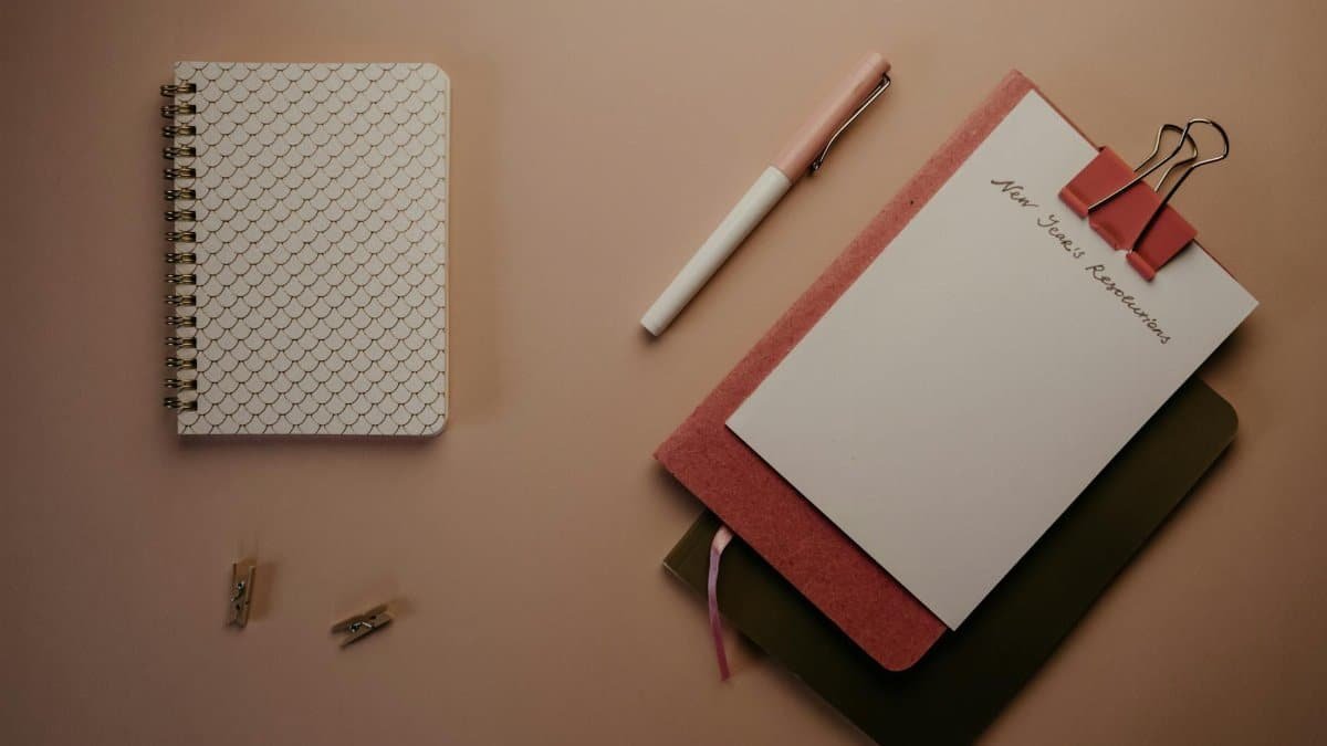 Organized flatlay of notebooks and pen for planning New Year's resolutions.