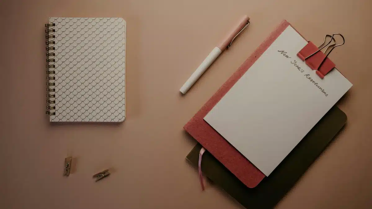 Organized flatlay of notebooks and pen for planning New Year's resolutions.